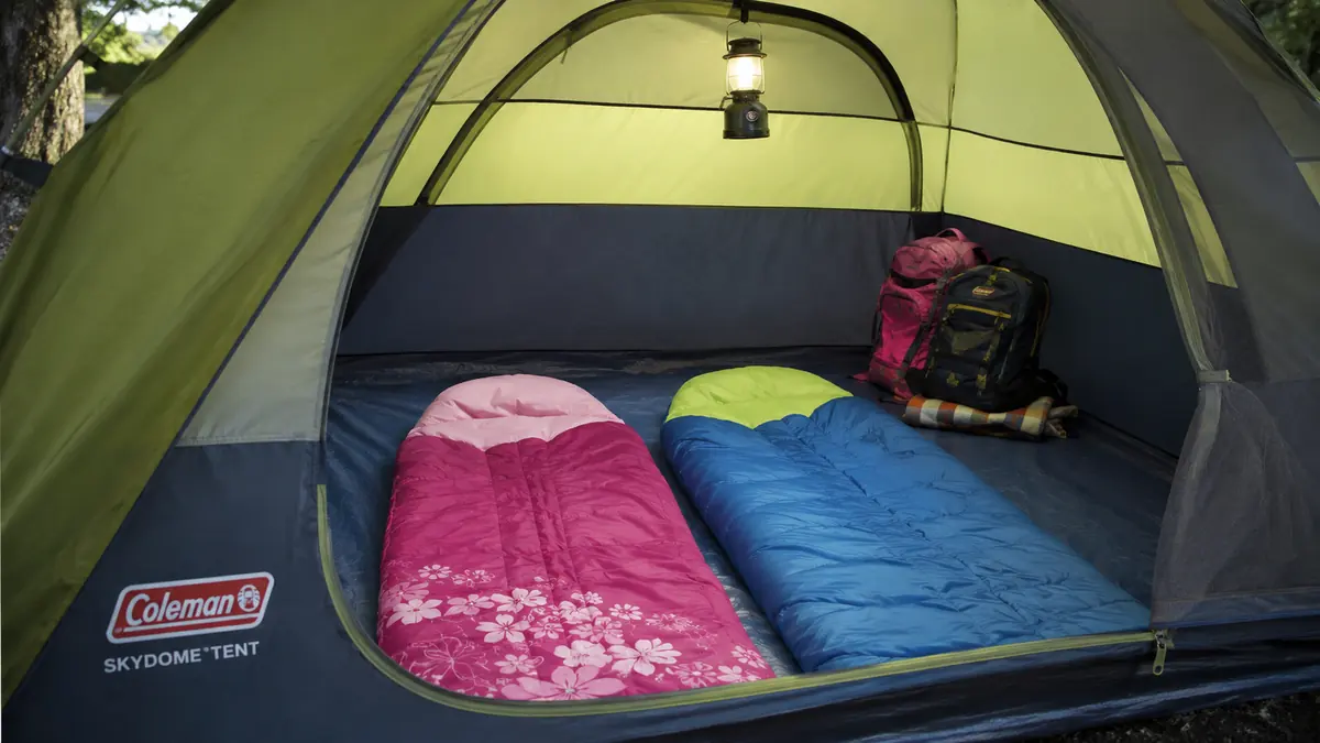 Interior of the Coleman Skydome tent showing two kids' sleeping bags laid out with gear in the corner